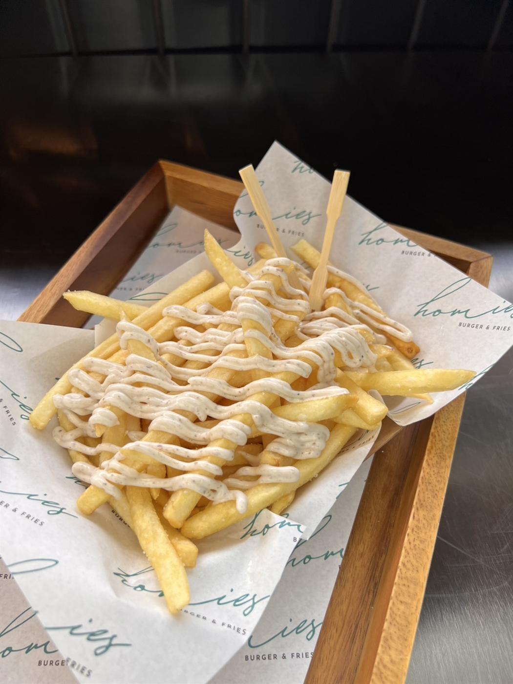 Loaded fries with creamy sauce on Homies branded paper